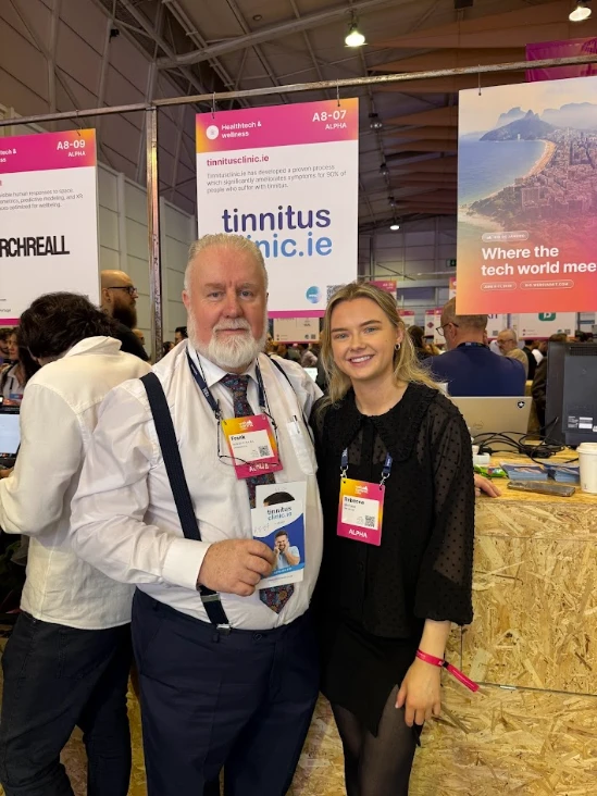 Two people at the tinnitusclinic.ie booth at a healthtech & wellness event. Signage reads "tinnitusclinic.ie.